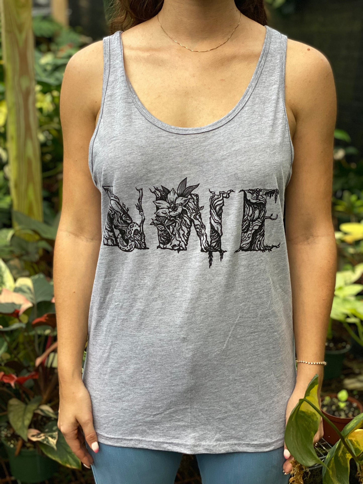 Woman wearing a gray NWE Logo Tank Top featuring a hand-drawn botanical floral monogram by Ashley Simone.