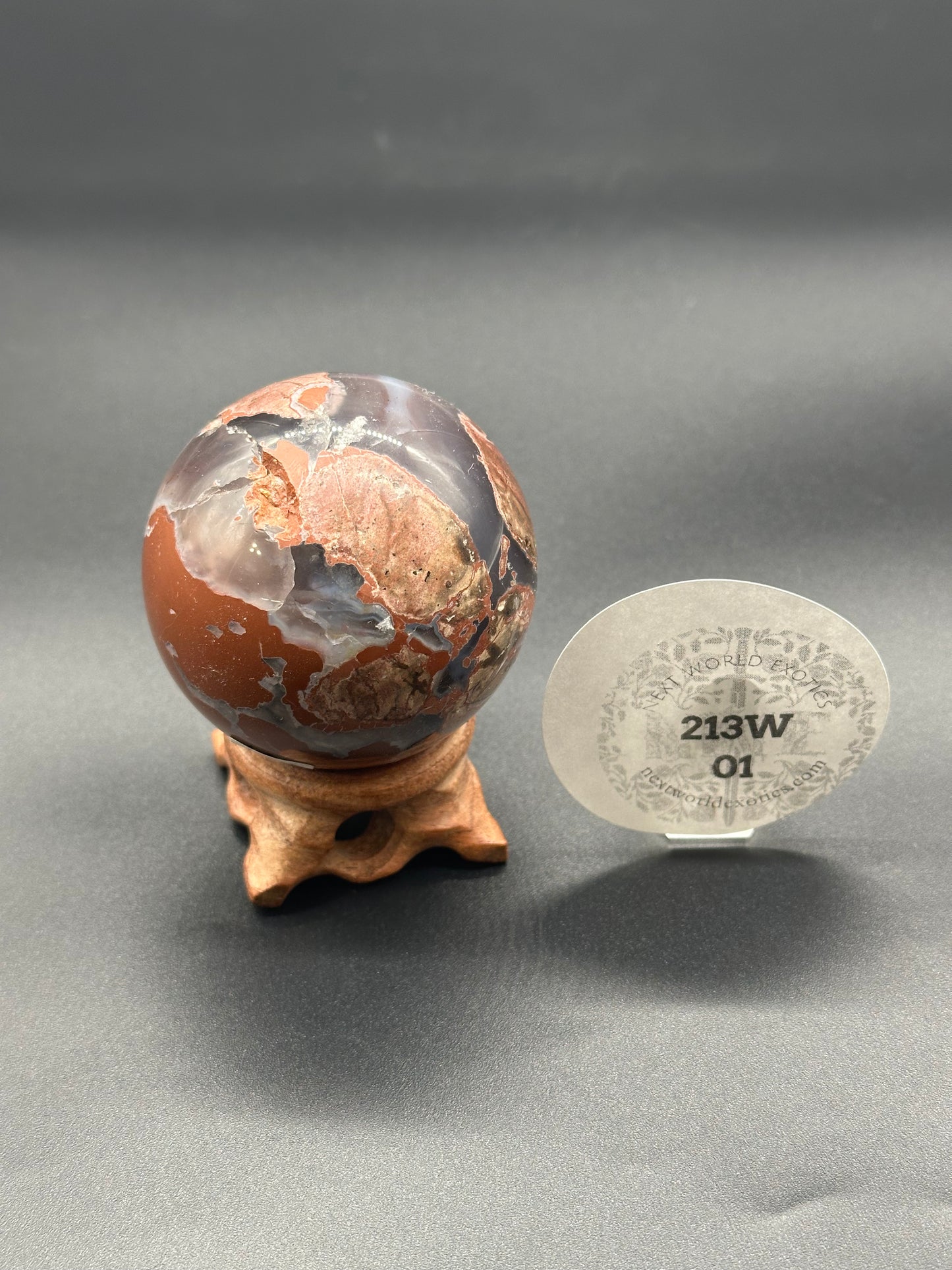 Red Jasper Agate Sphere (213W01) depicted as a globe-like object on a stand, highlighting its smooth, map-like surface in a still life setting.