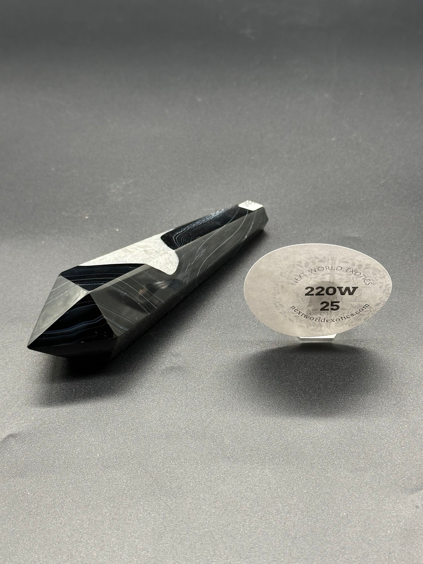Black Agate Scepter (220W25) displayed alongside a circular sticker, showcasing its unique black and white stone texture.