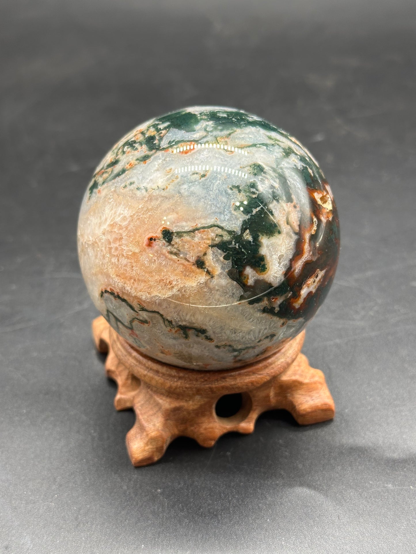 Red Moss Agate Sphere (1126W33) displayed on a stand, showcasing its polished marble-like appearance.
