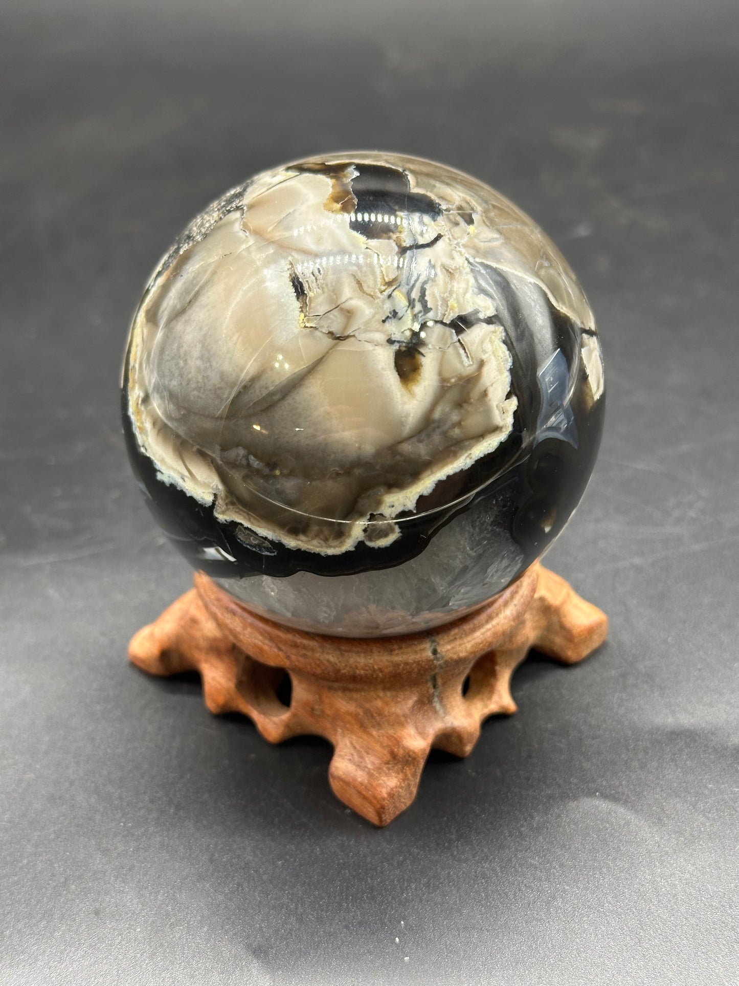 Volcanic Agate Sphere (1126W31) displayed on a wooden stand, showcasing its smooth, round surface, ideal for artful mineral collections or decor.