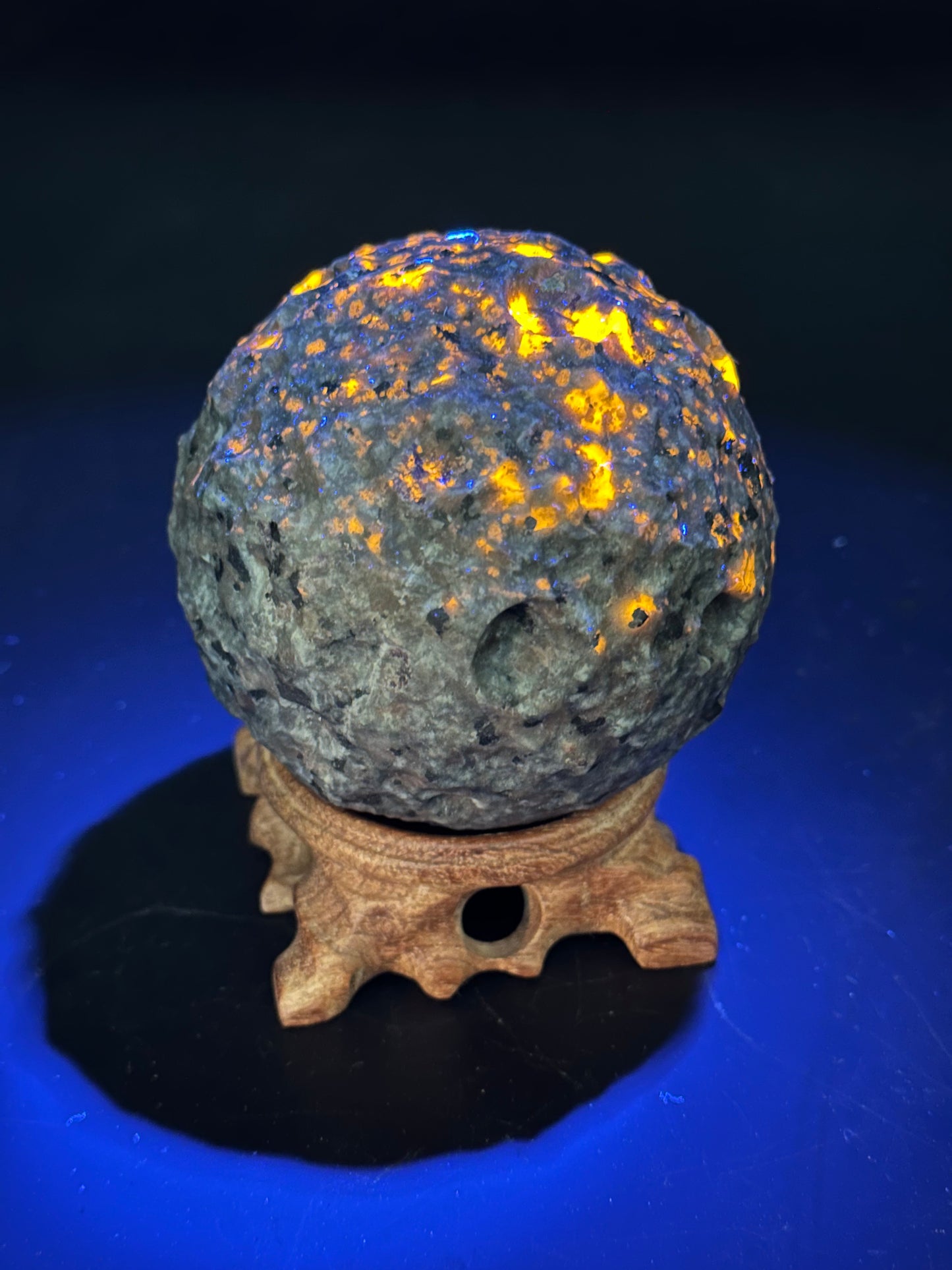 Yooperlite Moon Carving (1126W32) featuring a rock with glowing yellow lights, displayed on a stand, capturing the enchanting allure of this unique mineral carving.