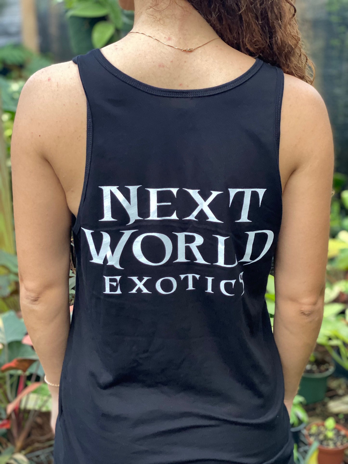 Woman wearing Black NWE Logo Tank Top with botanical floral monogram, featuring a gold necklace.