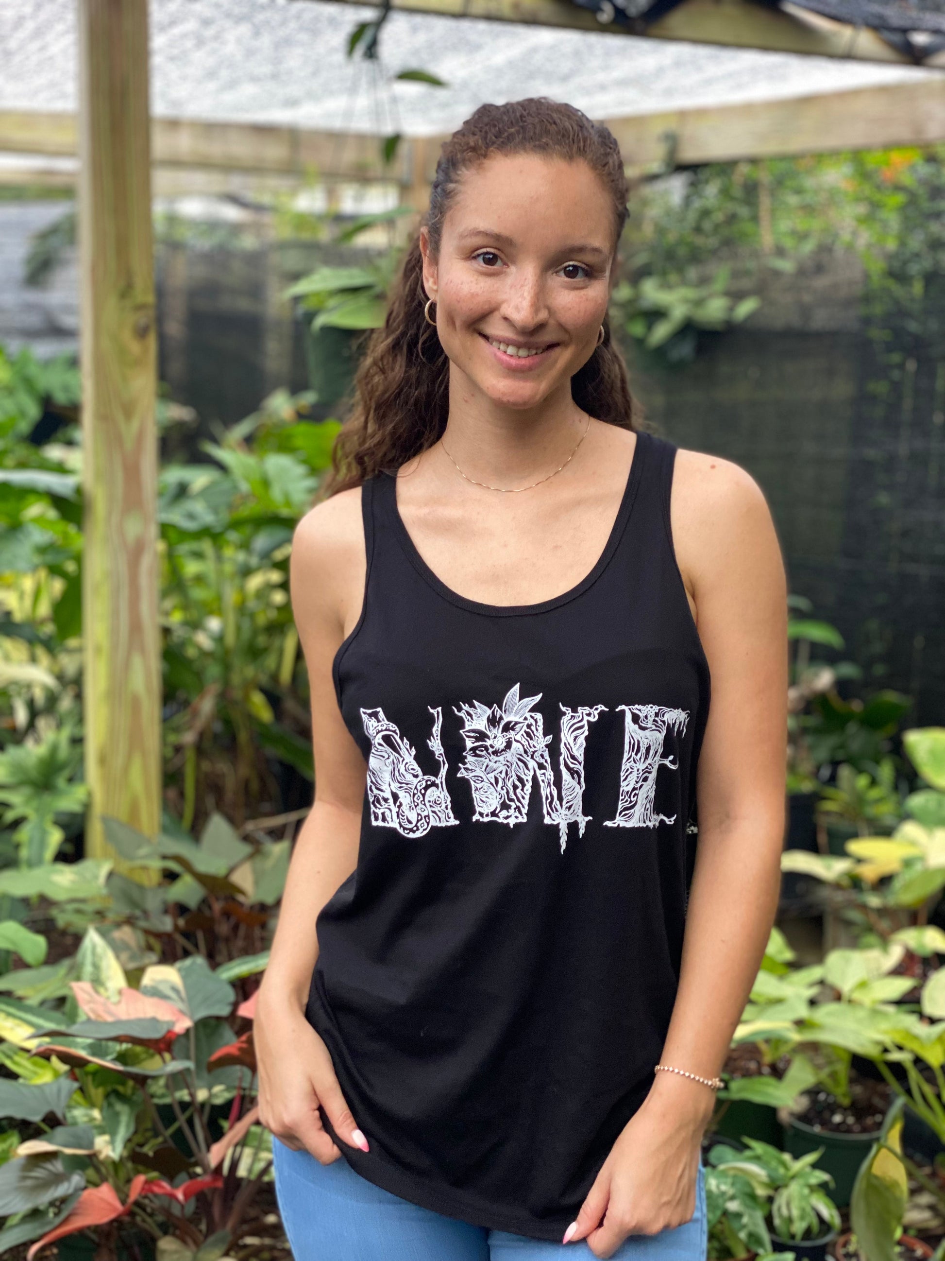 Woman smiling, wearing a black tank top with a hand-drawn botanical floral monogram logo.