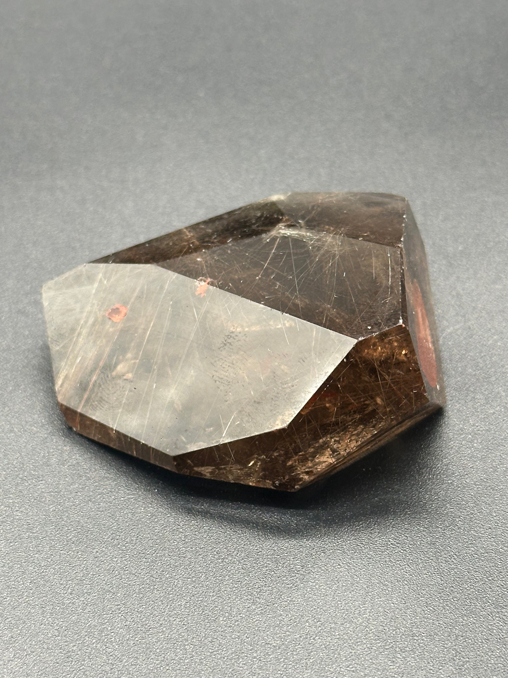 Rutilated Smokey Garden Quartz (213W05) crystal displayed on a surface, showcasing intricate mineral patterns and textures.