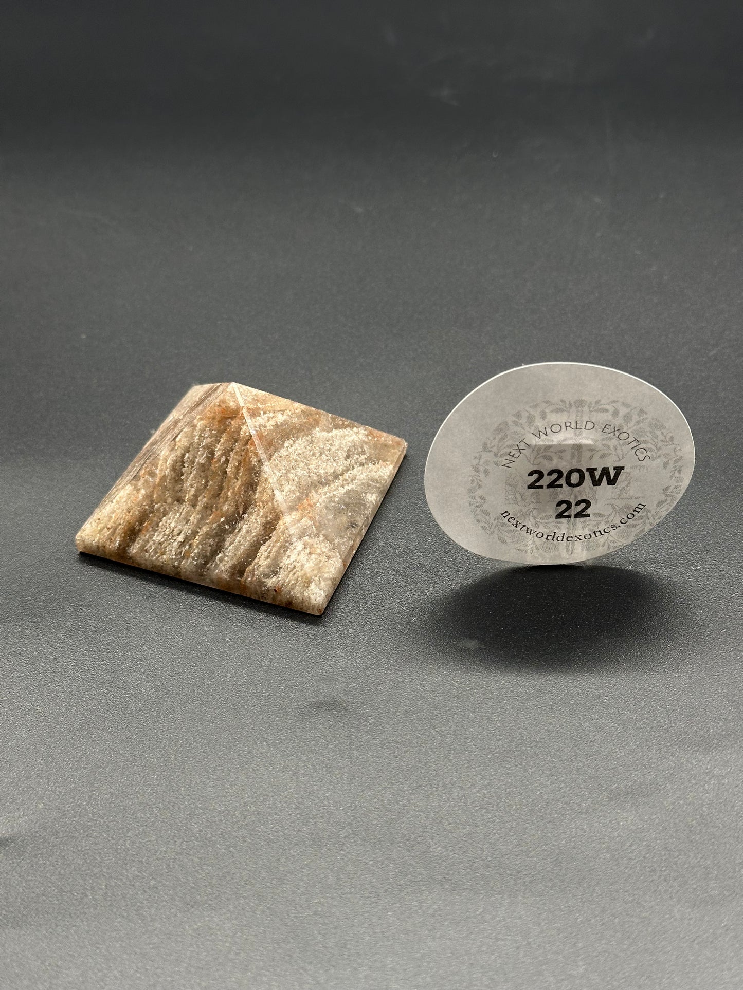 Thousand Layer Quartz Pyramid (220W22) close-up showing intricate stone layers and a label with text and numbers, emphasizing its detailed craftsmanship.