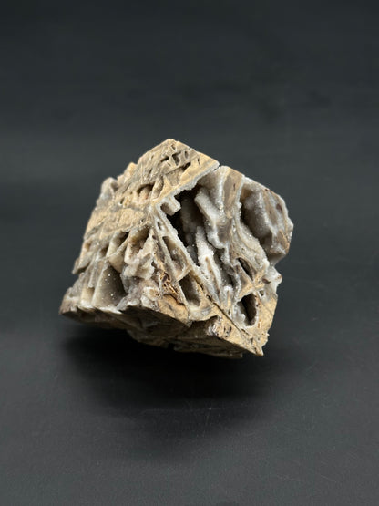 Sphalerite Cube (812W05) featuring a cube-shaped mineral specimen with vugs lined with tiny sparkly quartz crystals on a weathered tan-beige host rock.
