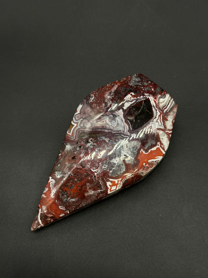 Mexican Crazy Lace Agate Free Form (812W09), a polished, elongated oval cabochon, showcases intricate swirling patterns, highlighting its natural banded and brecciated textures.