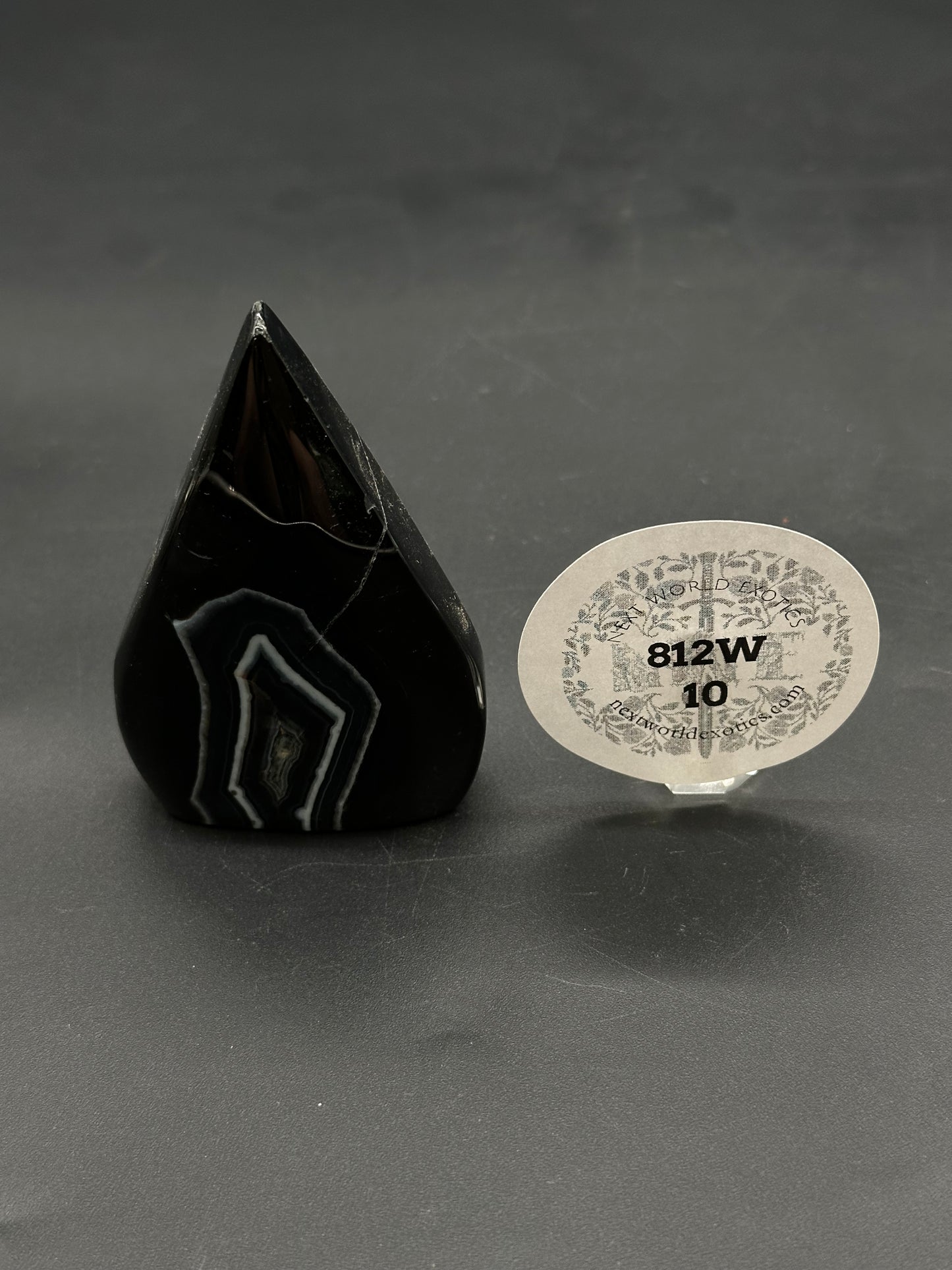 Black Agate Free Form (812W10) carved into a rounded-teardrop shape, set upright, with a small round tag reading “812W 10” nearby.