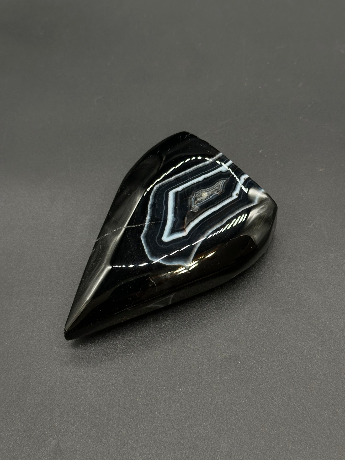 Black Agate Free Form (812W10) teardrop gemstone, polished to reveal distinctive concentric white-and-gray bands surrounded by glossy black chalcedony.