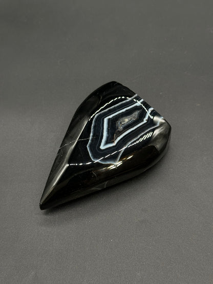 Black Agate Free Form (812W10) teardrop gemstone, polished to reveal distinctive concentric white-and-gray bands surrounded by glossy black chalcedony.