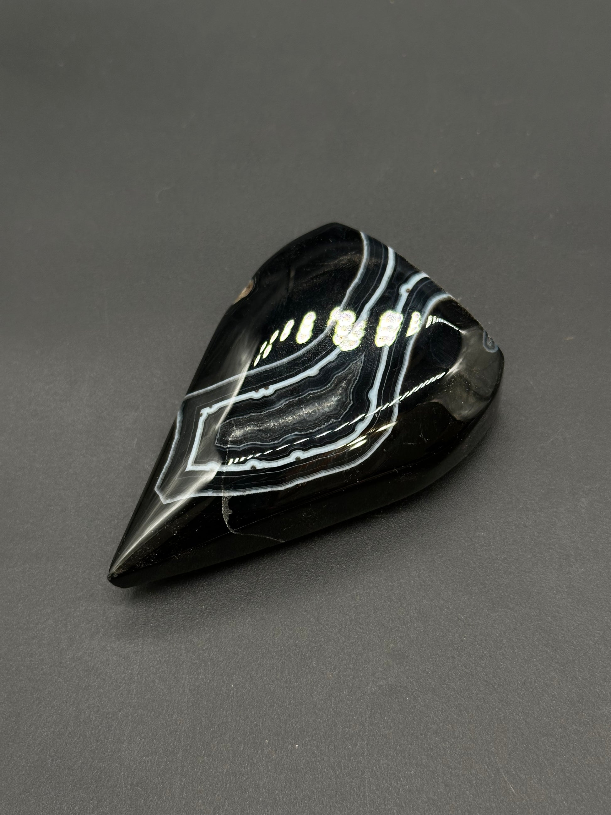 Black Agate Free Form (812W10) gemstone, teardrop-shaped with glossy black surface and striking white/grey banding, polished to perfection.