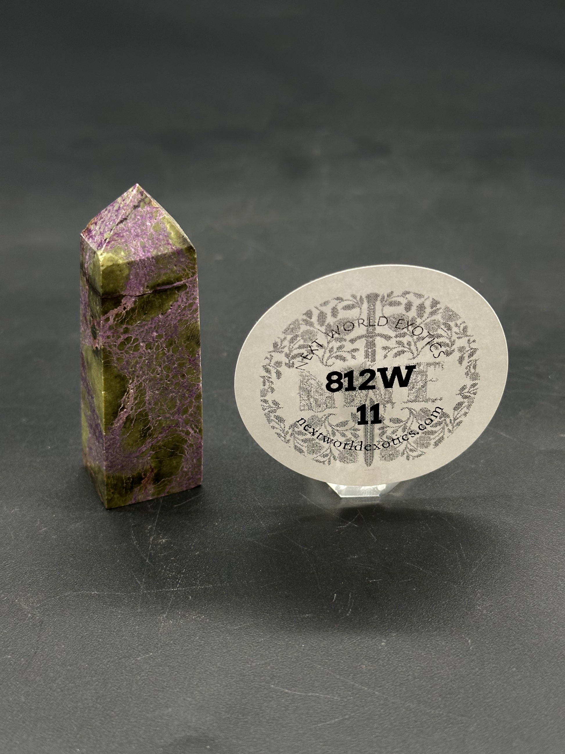 Atlantisite Tower (812W11) stands elegantly, crafted from purple-and-green mineral, with a clear label from Next World Exotics beside it.