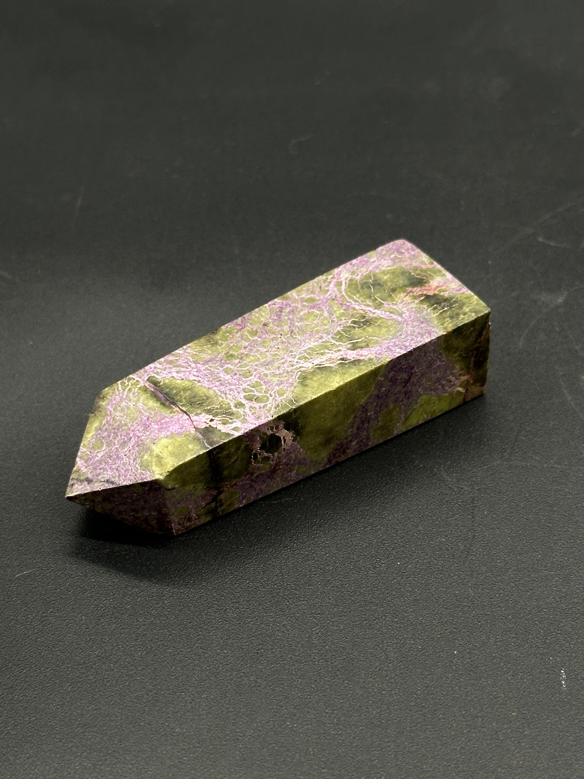 Atlantisite Tower (812W11) as a small, double-terminated crystal with a six-sided prism, showcasing mottled surface of olive-green and lavender-purple veins.