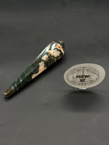 Red Moss Agate Scepter (812W12) shown as a polished hexagonal crystal wand with dark green and creamy white patterns, resting on a black mat.