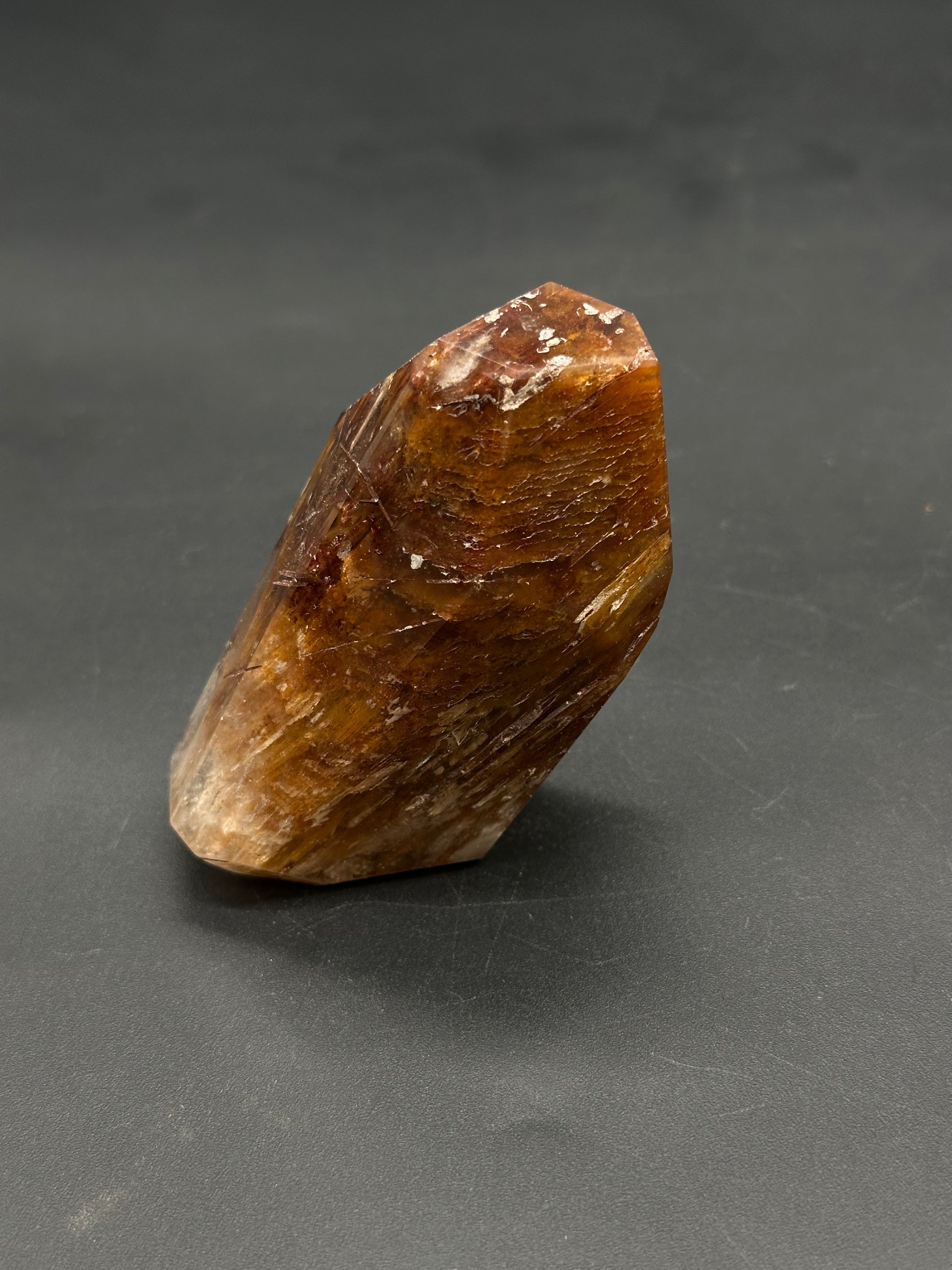 Rabbits Hair Quartz (812W15), a faceted, hand-sized, hexagonal prism with natural striations, showcasing the golden healer crystal's polished point on a matte surface.