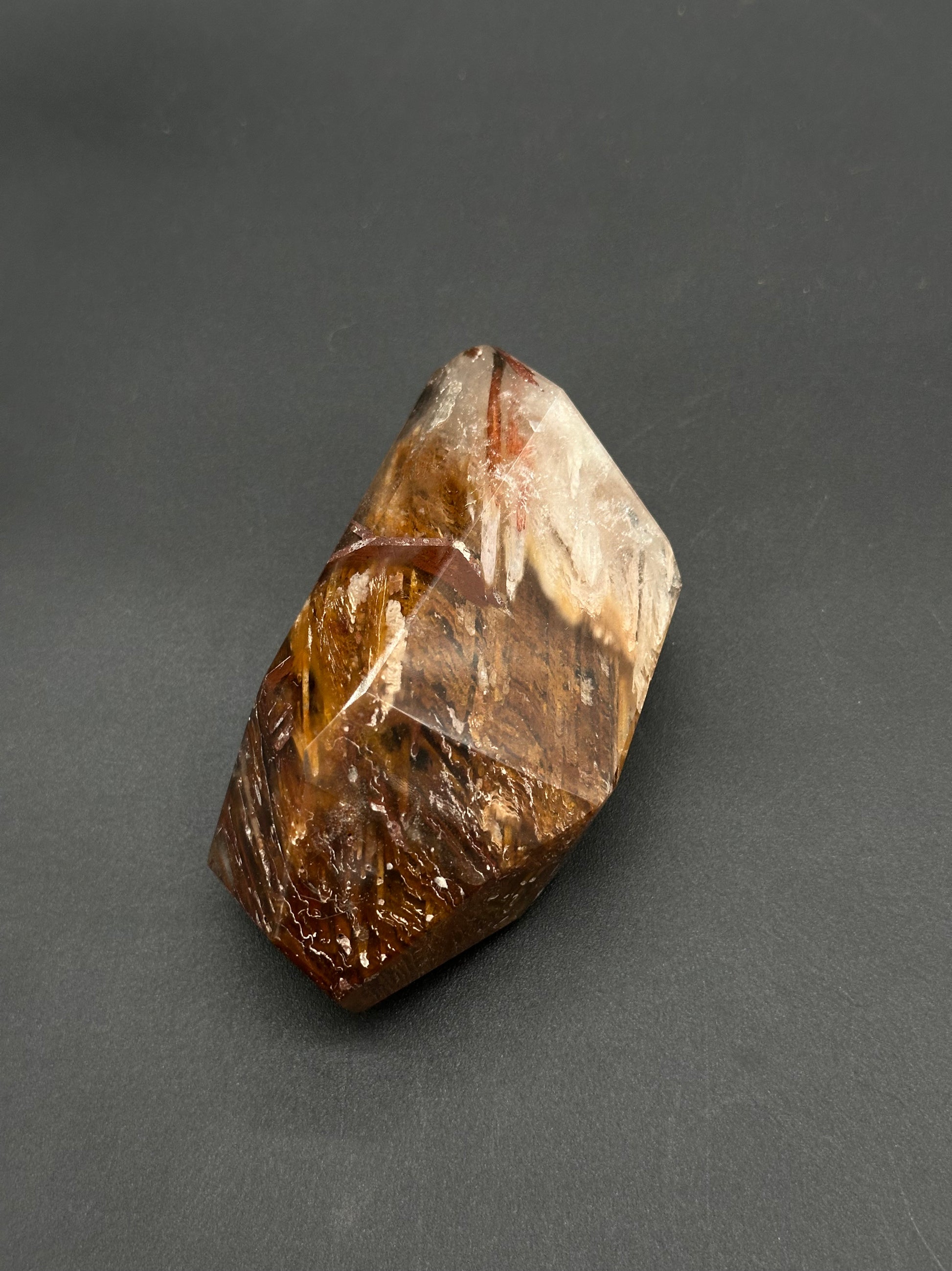 Rabbits Hair Quartz (812W15) features a polished hexagonal crystal point with smoky quartz clarity and rich brown-gold inclusions, ending in a translucent glassy tip.