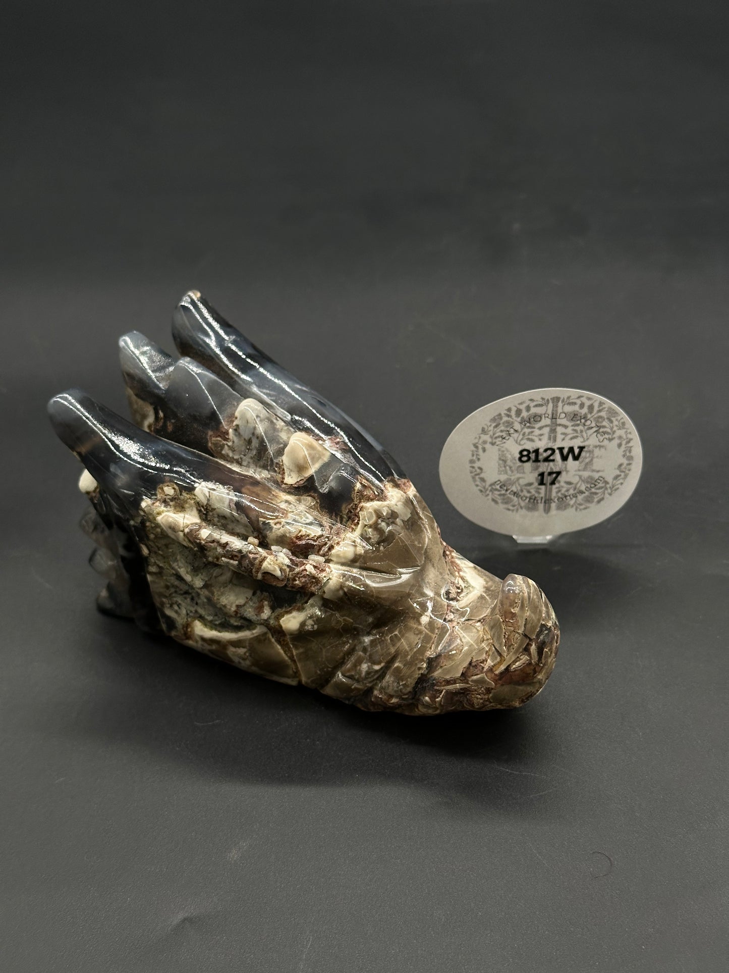 Volcanic Agate Dragon Carving (812W17) showcasing a detailed dragon head sculpture in mottled mineral, set beside a small oval display tag, against a dark background.