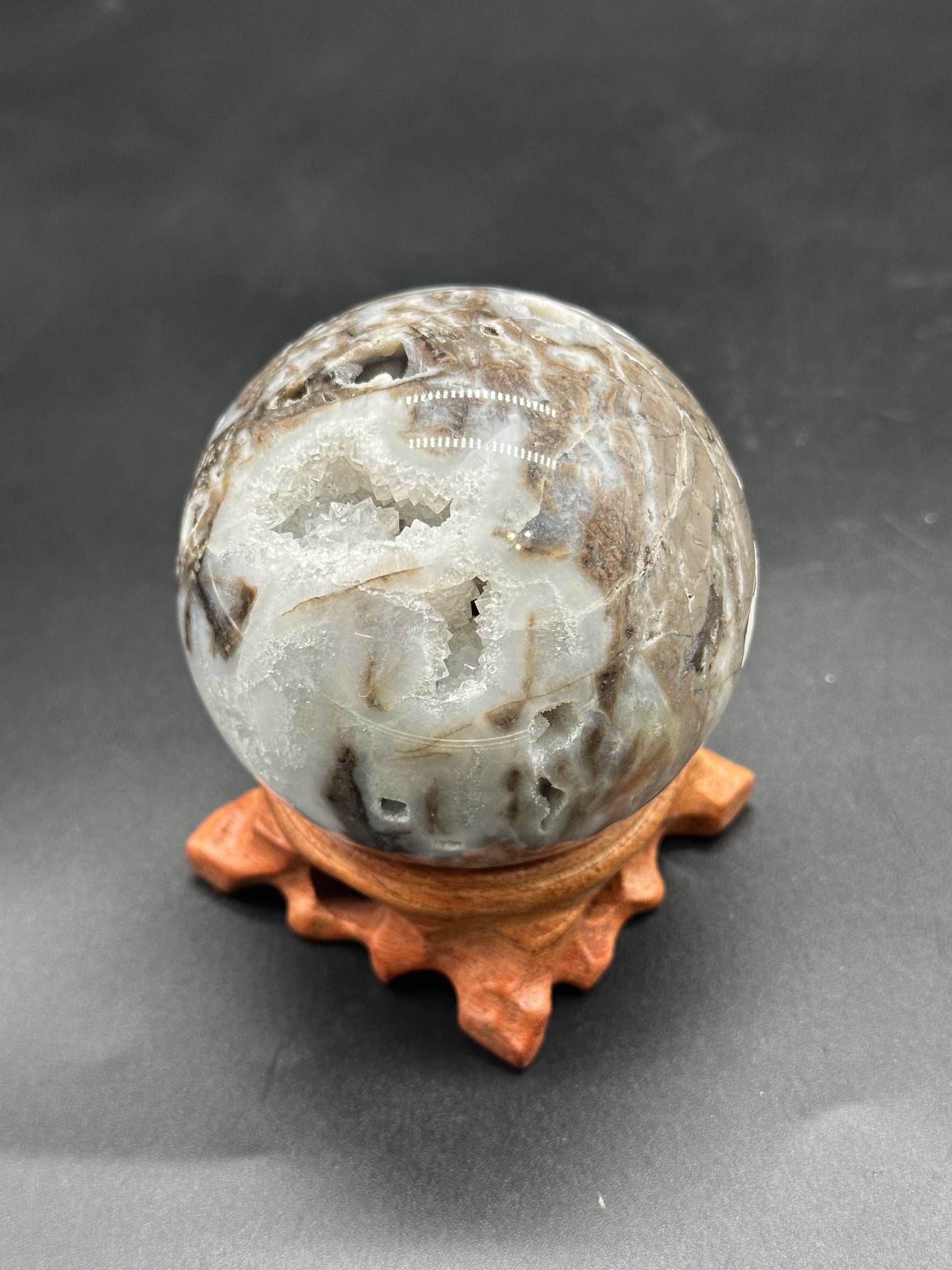 Sphalerite Sphere (1114W09) on a stand, showcasing a 2.65-inch diameter with a visible druzy cavern detail, captured in a close-up.