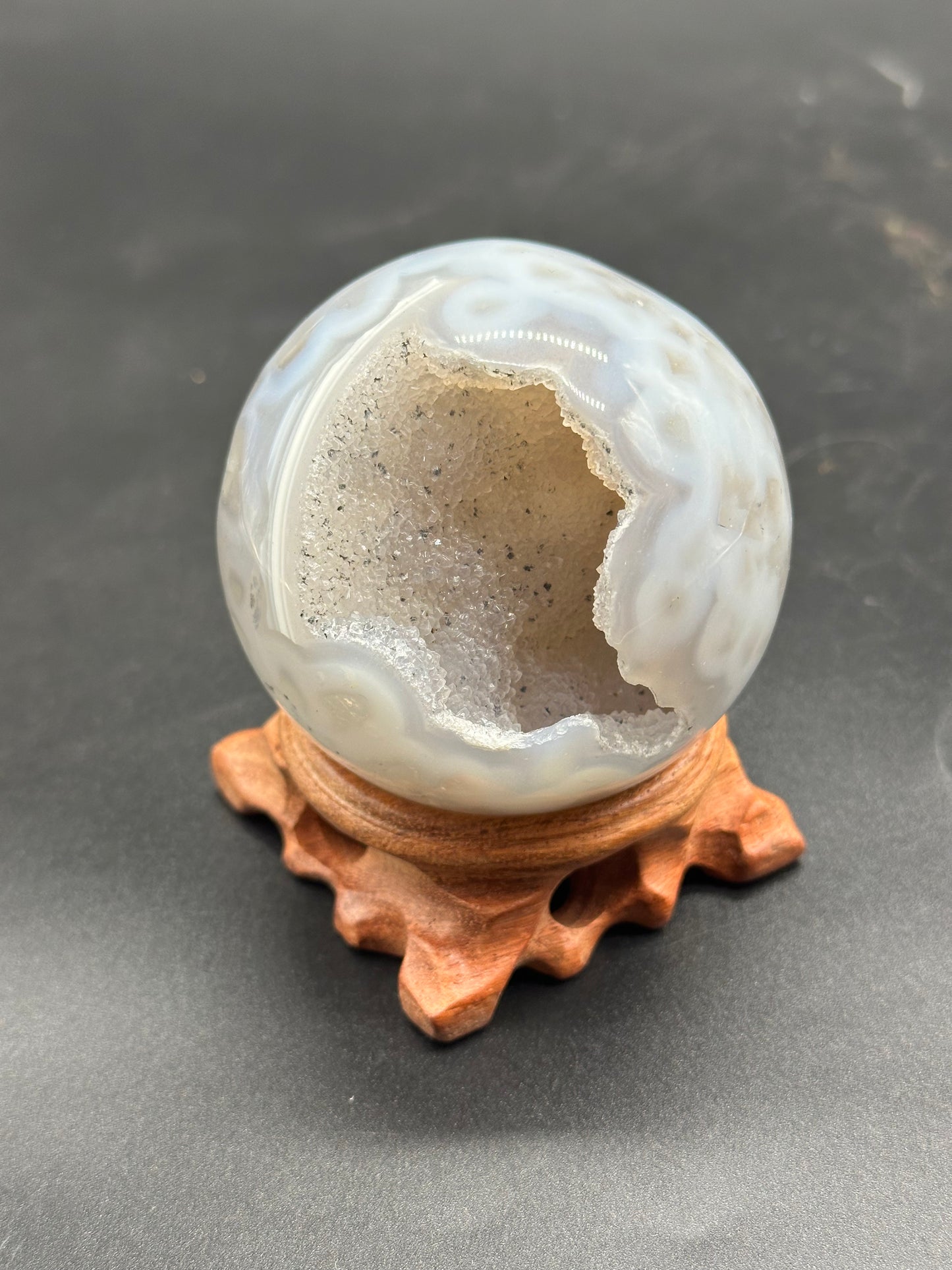 Agate Sphere with Duzy Caverns (1024W43) featuring a central hole, showcasing intricate details, highlighting its mineral composition and unique structure.