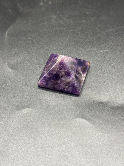 Amethyst Pyramid (103W46), a pyramid-shaped amethyst crystal with a polished surface, displayed on a textured grey background.