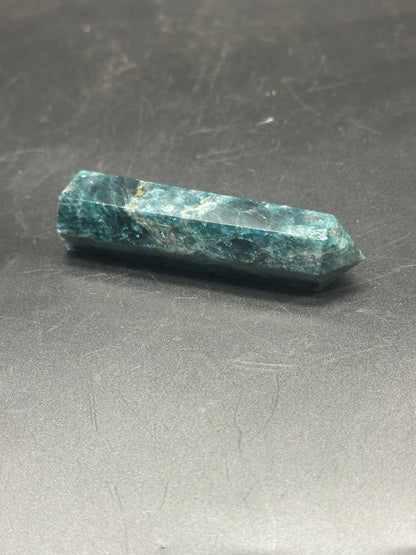 Blue Apatite Tower (103W48) – a polished, pointed crystal with intricate patterns and a smooth surface, displayed on a neutral background.