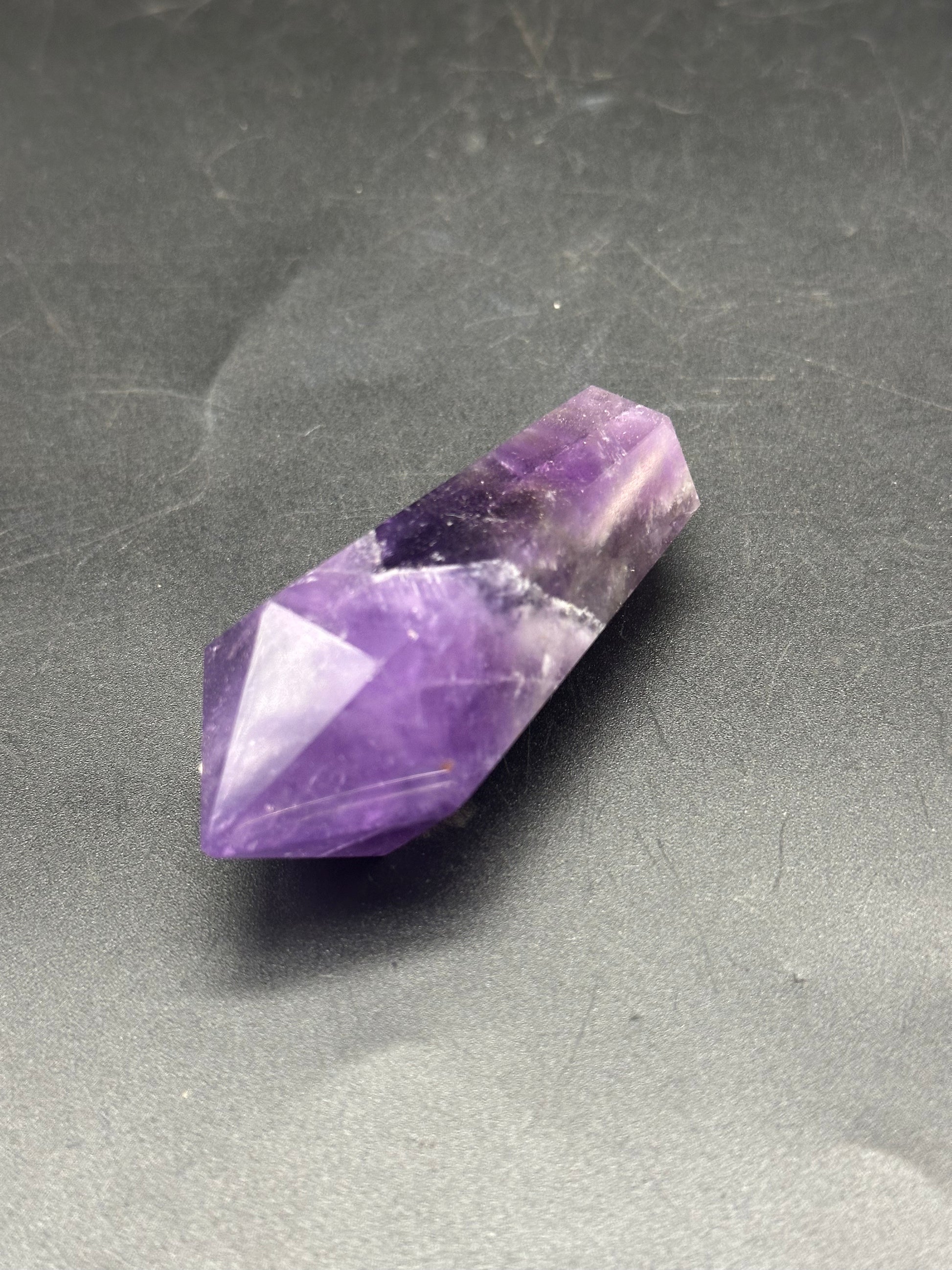 Double Terminated Fluorite (1212W24) crystal displayed on a surface, showcasing its distinct structure and refined edges, ideal for collectors and enthusiasts.