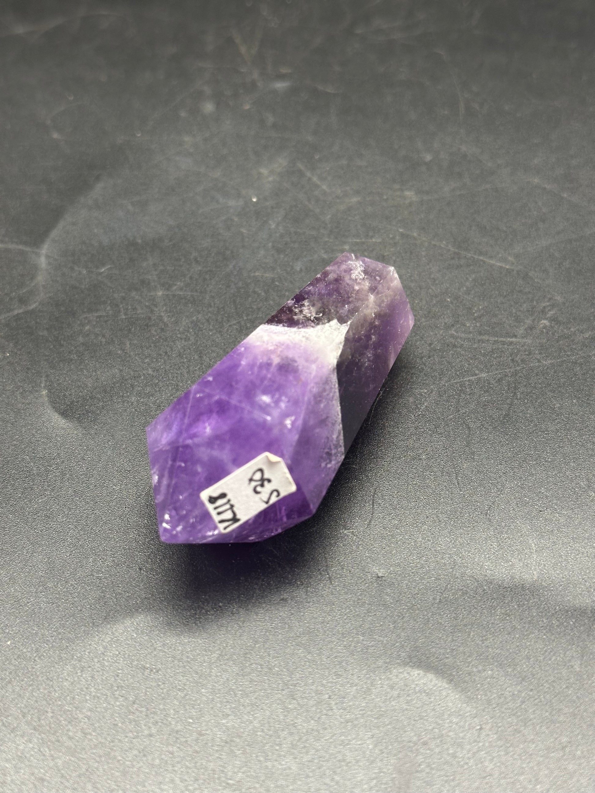Double Terminated Fluorite (1212W24) crystal with a visible price tag placed on a dark surface.
