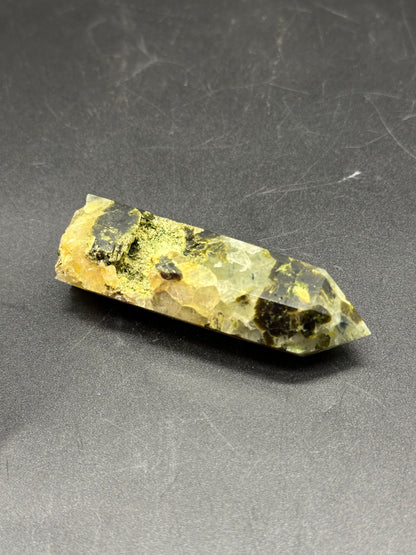 Epidote and Prehnite Tower (1017W46) displayed on a black surface, showcasing its crystalline structure with intricate textures.