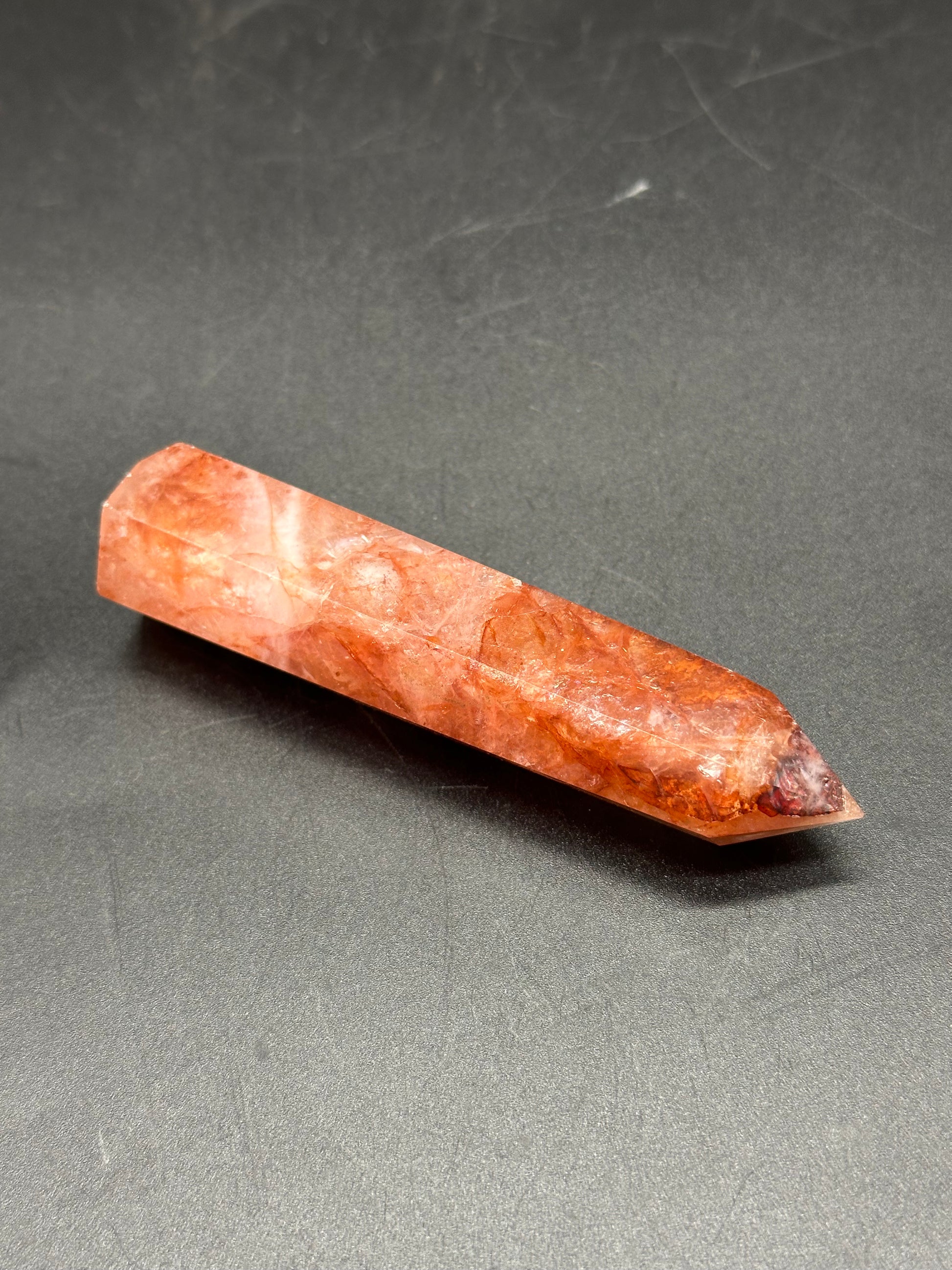 Fire Quartz Tower (1017W44) crystal point displayed on a dark surface, showcasing its natural structure and polished finish. Ideal for collectors and enthusiasts.