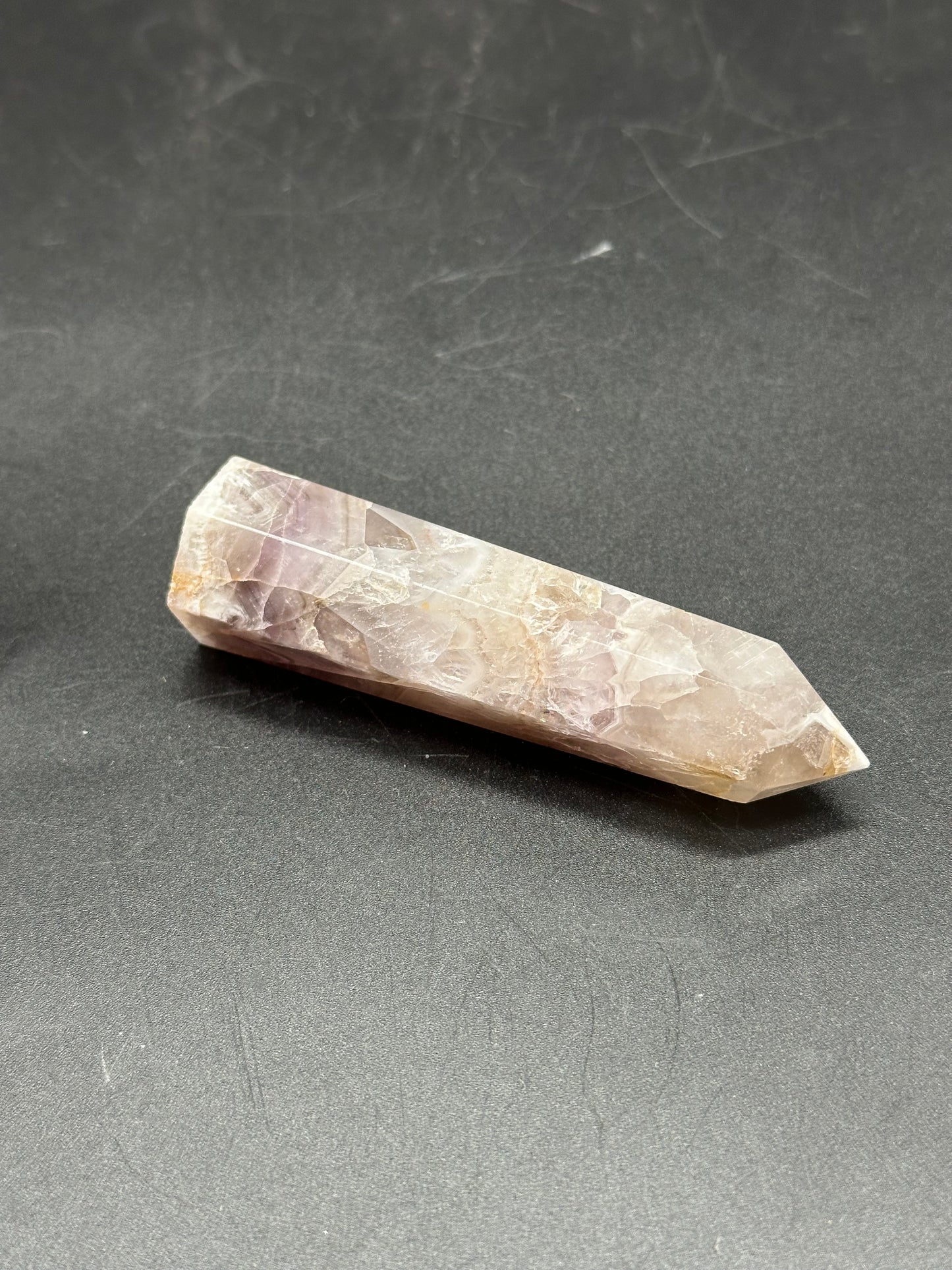 Flower Agate Tower (1017W49) crystal point displayed on a black surface, highlighting its intricate patterns and unique stone structure.