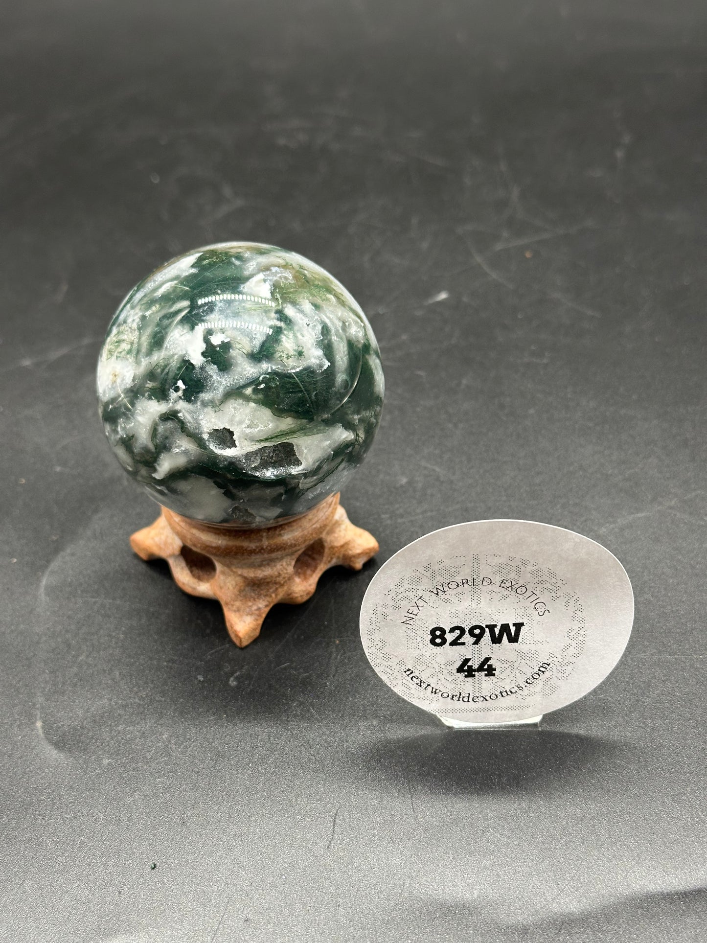 Moss Agate Sphere (829W44) on a stand, showcasing its marbled appearance.