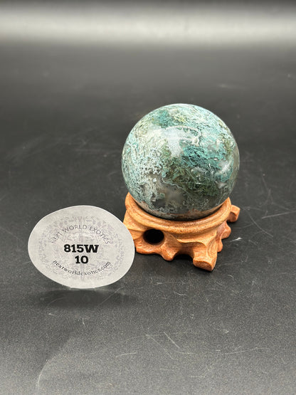 Moss Agate Sphere (815W10) displayed on a wooden stand, featuring a marbled pattern and a white sticker with black text and numbers.