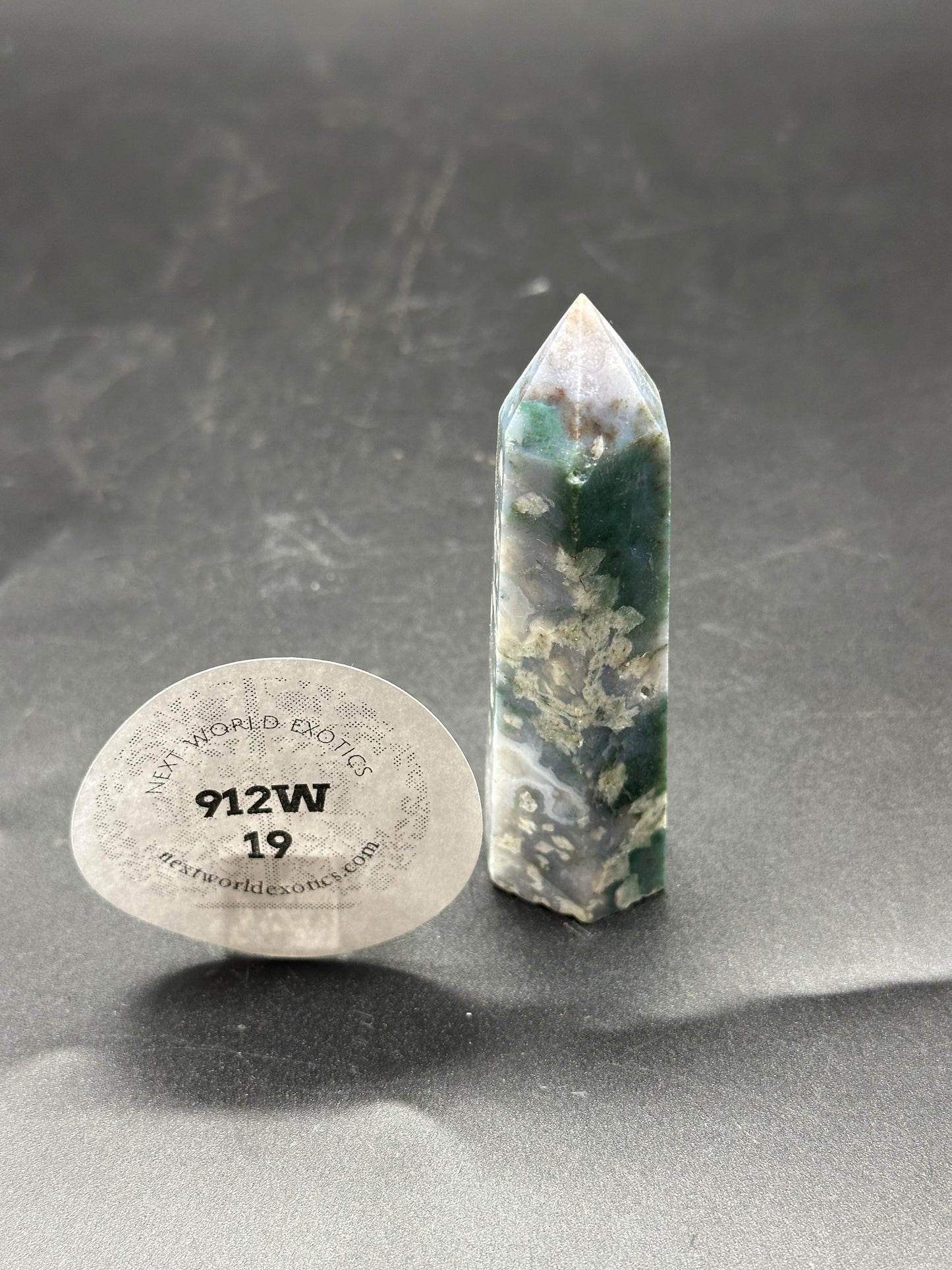 Moss Agate Tower (912W19) crystal with a pointy top and a round label sticker, showcased up-close.