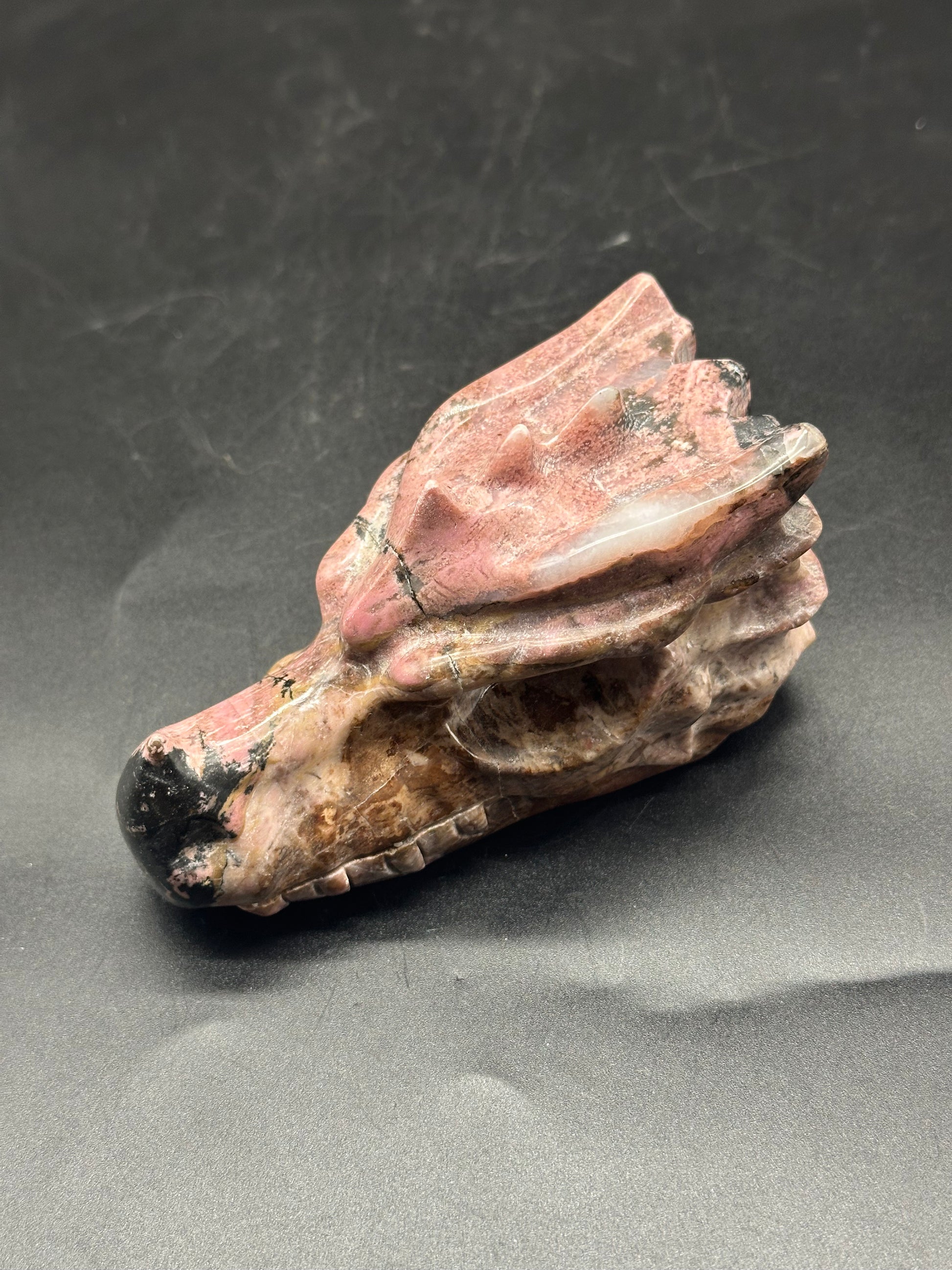 Pink Rhodonite Dragon Head (103W45) intricately carved, showcasing detailed features resembling a dragon's skull in a polished stone finish.