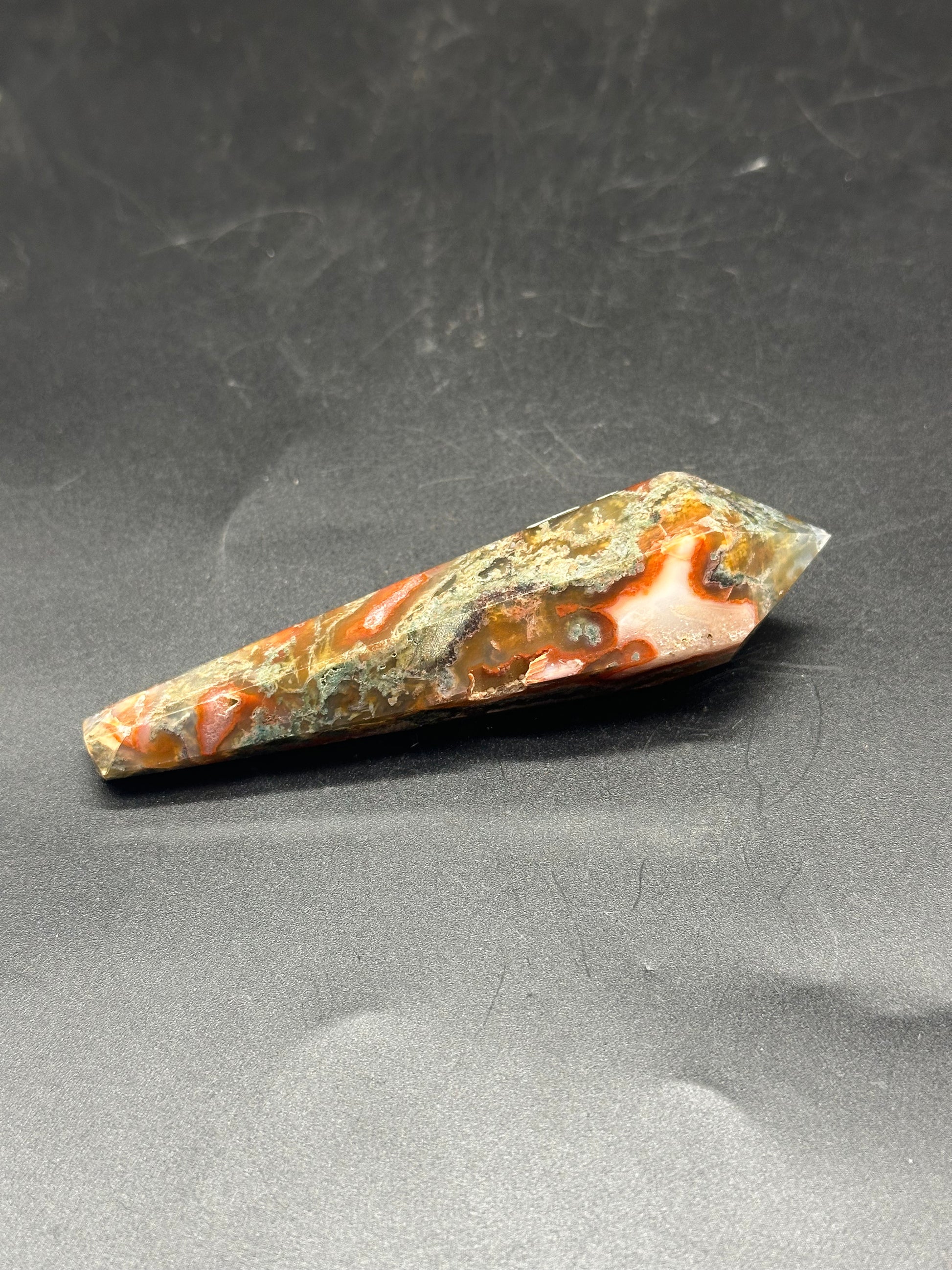 Red Moss Agate Scepter (103W48) featuring intricate orange and white crystal patterns on a rectangular surface, displayed against a black background with white spots.