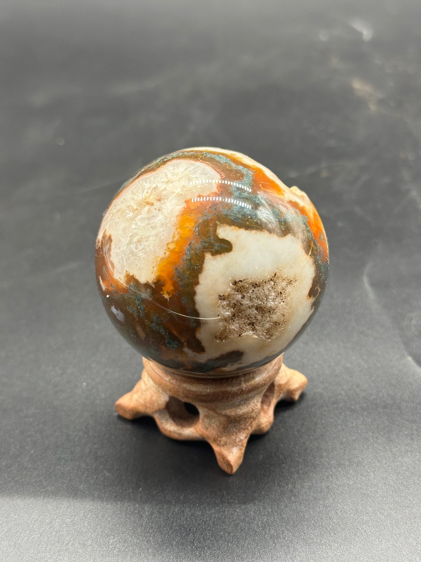 Red Moss Agate Sphere (1024W45) displayed on a stand, showcasing its smooth, round stone surface, emphasizing its artistic and mineral characteristics.