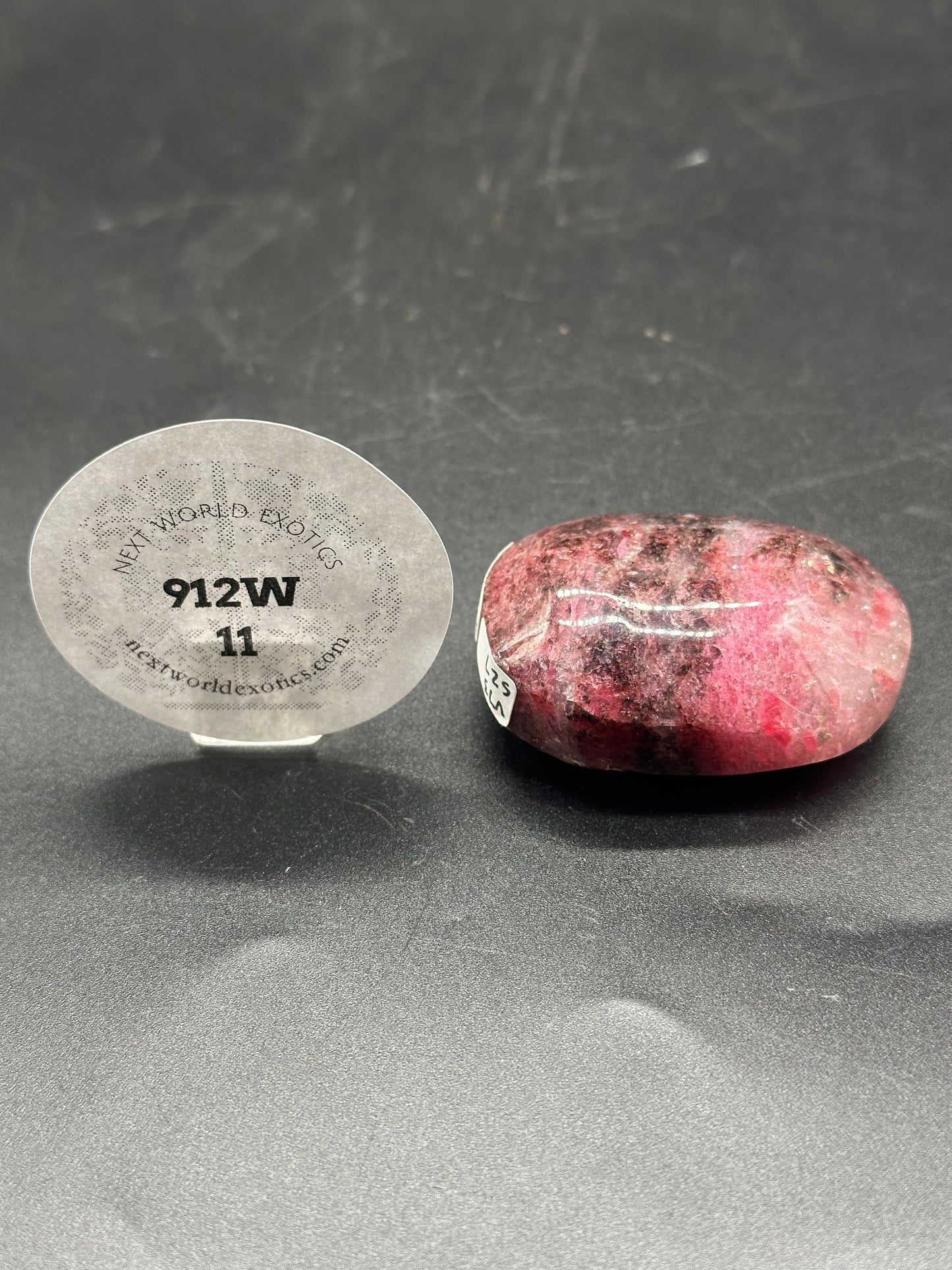 Rhodonite Palm Stone (912W11) with a circular label displaying numbers and letters, highlighting its unique texture and geological significance.