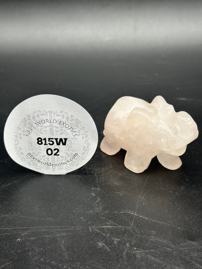 Rose Quartz Elephant (815W02) figurine displayed next to a round white object, set against a black surface.