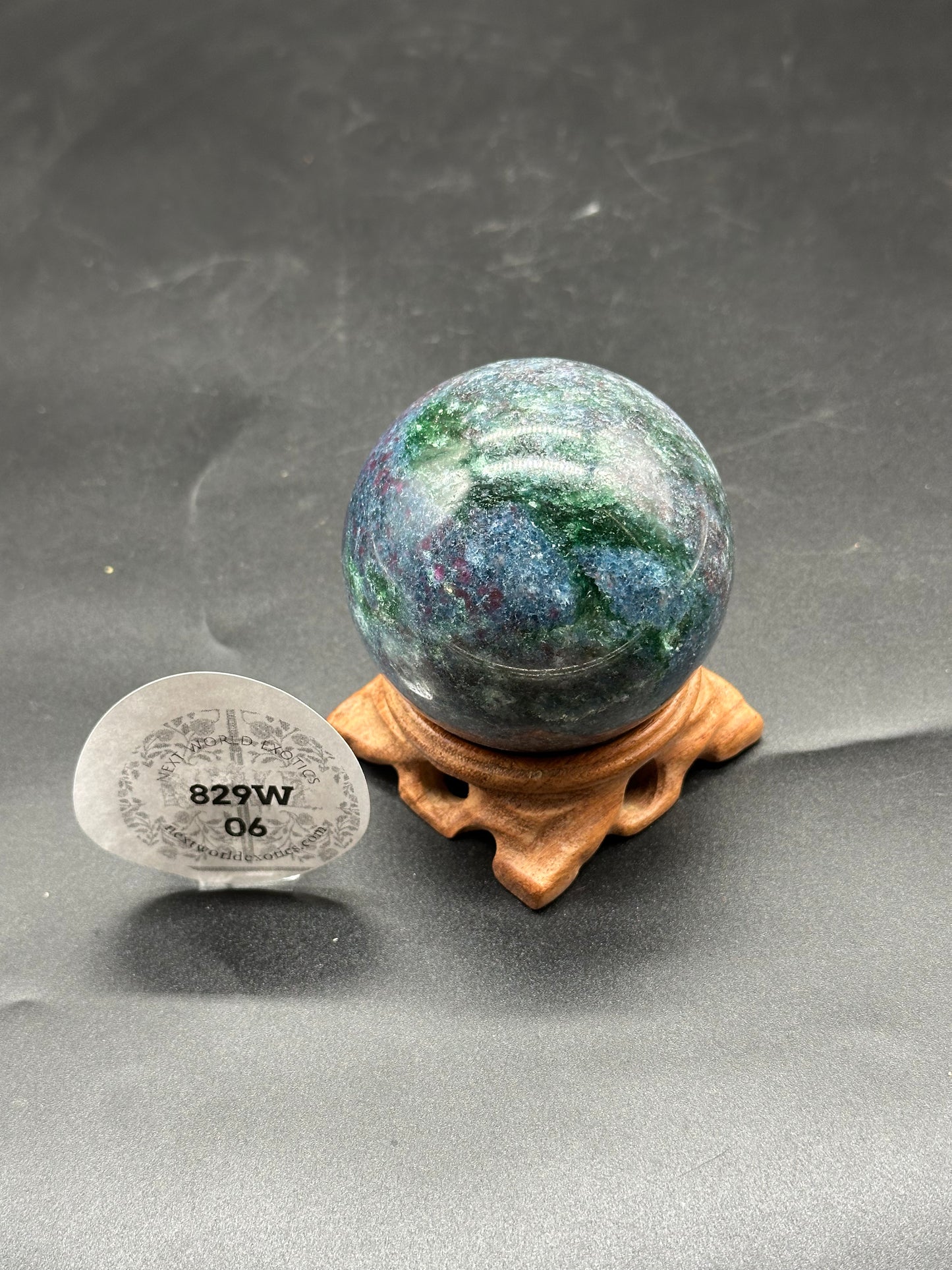 Ruby Kyanite Sphere (829W06) on a wooden stand, showcasing its polished, spherical form, ideal for home decor or personal collections.