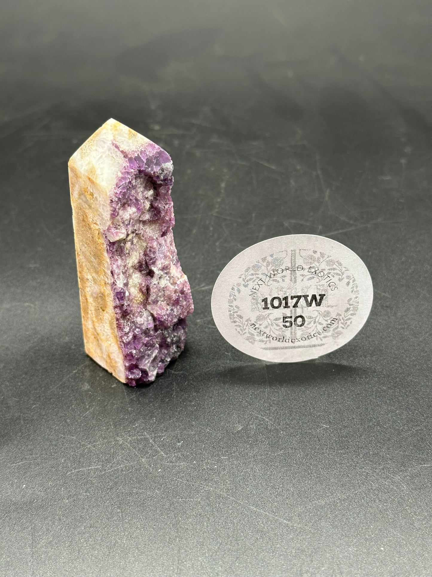 Specimen Fluorite Tower (1017W50) beside a white disc with black text, showcasing its distinct mineral texture and unique structure.