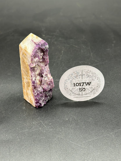 Specimen Fluorite Tower (1017W50) beside a white disc with black text, showcasing its distinct mineral texture and unique structure.