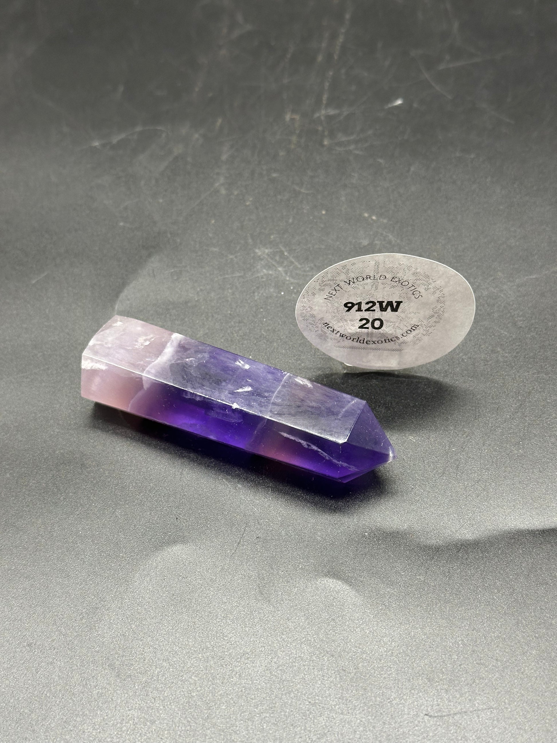 Violet Fluorite Tower (912W20) - A polished crystal tower with purple and white hues, showcased on a flat surface, ideal for decor or spiritual use.