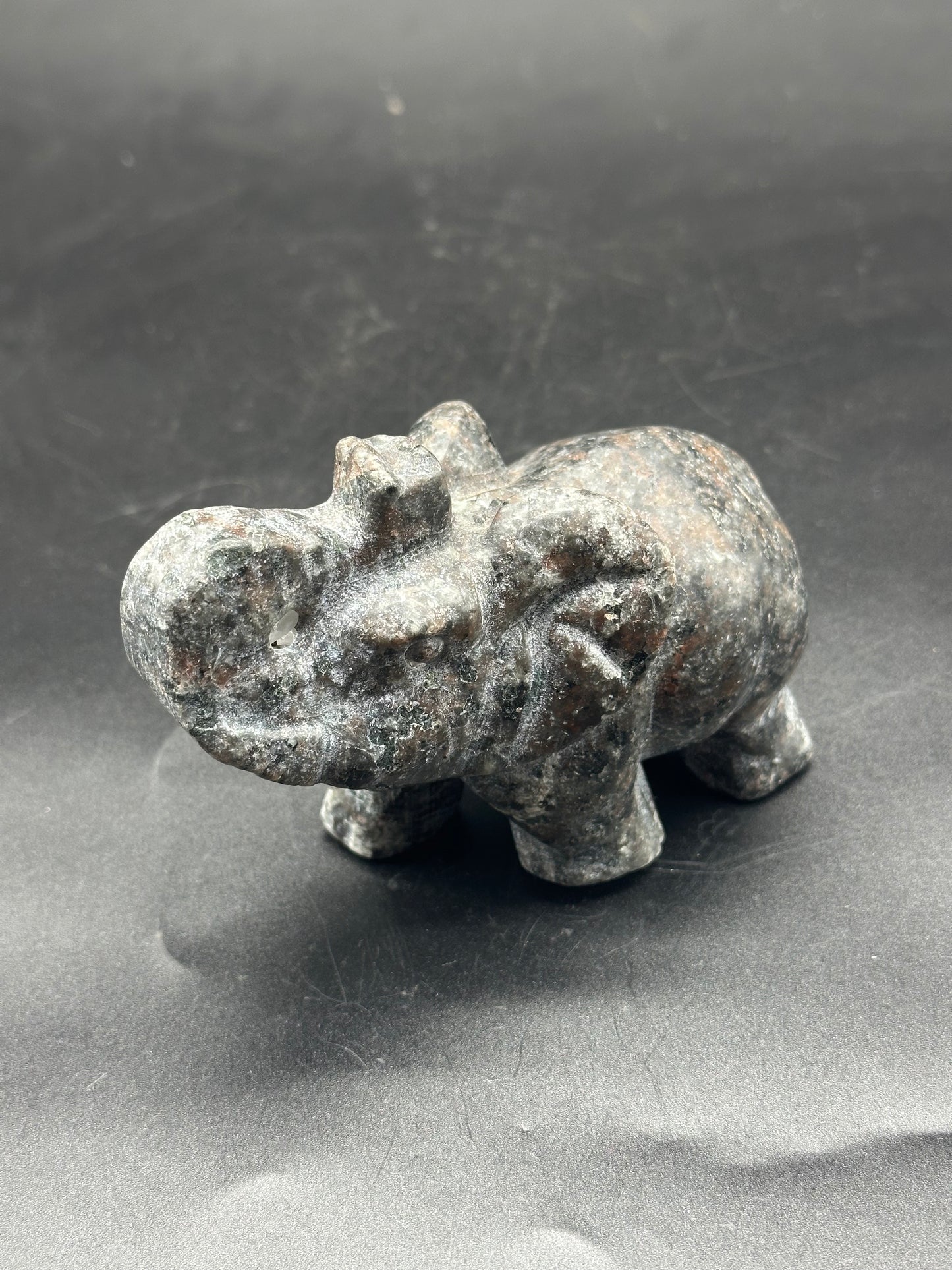 Yooperlite Elephant Carving (103W52) - a small stone elephant statue intricately carved, displayed on a surface.